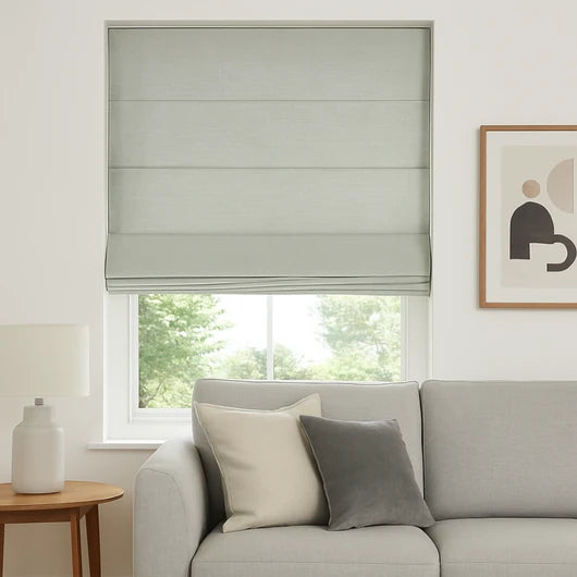 Modern light grey textured roman blinds installed in a bright living room, perfectly complementing a minimalist grey sofa and contemporary home decor.