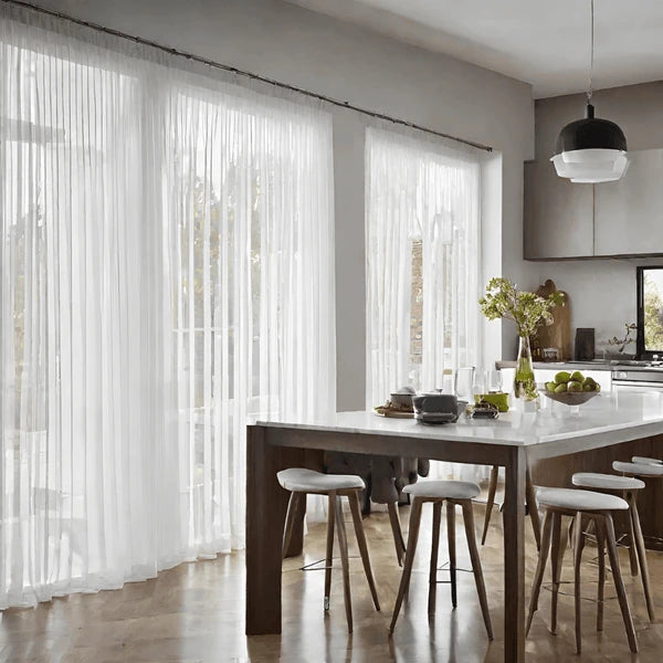 Modern open-plan kitchen and dining area featuring floor-to-ceiling white sheer curtains that provide elegant diffused light and a spacious feel.
