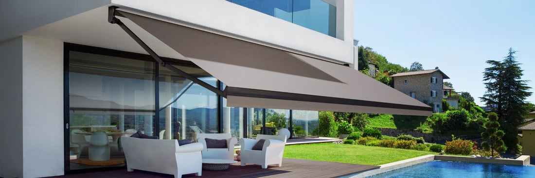 Modern grey retractable folding arm awning installed over a luxury poolside lounge area, providing sophisticated sun protection and outdoor comfort in Sydney.